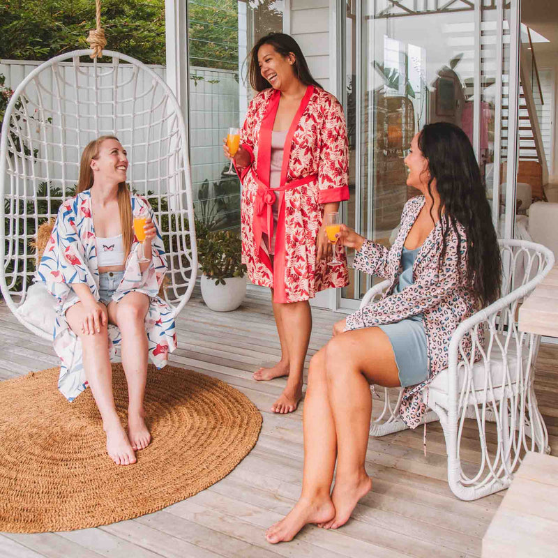Girls loungin around in the backdeck with red tropical short robe, white magnolia midi robe, leopard print short robe with mimosas